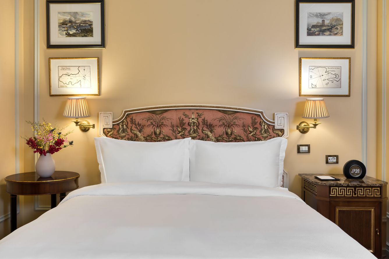 Cozy bed with floral headboard and framed wall art in a warmly lit room.