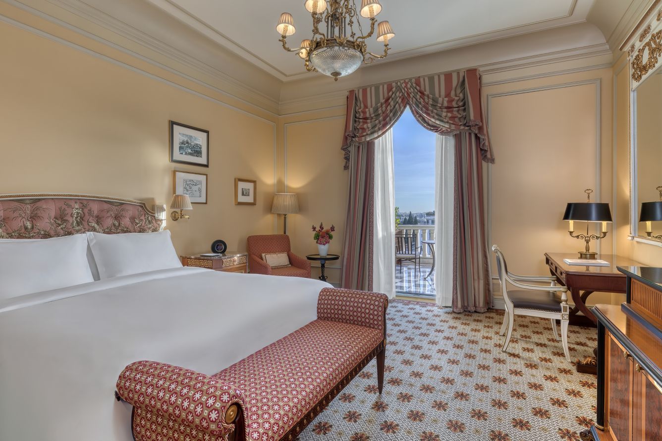Elegant hotel room with classic decor and balcony view.