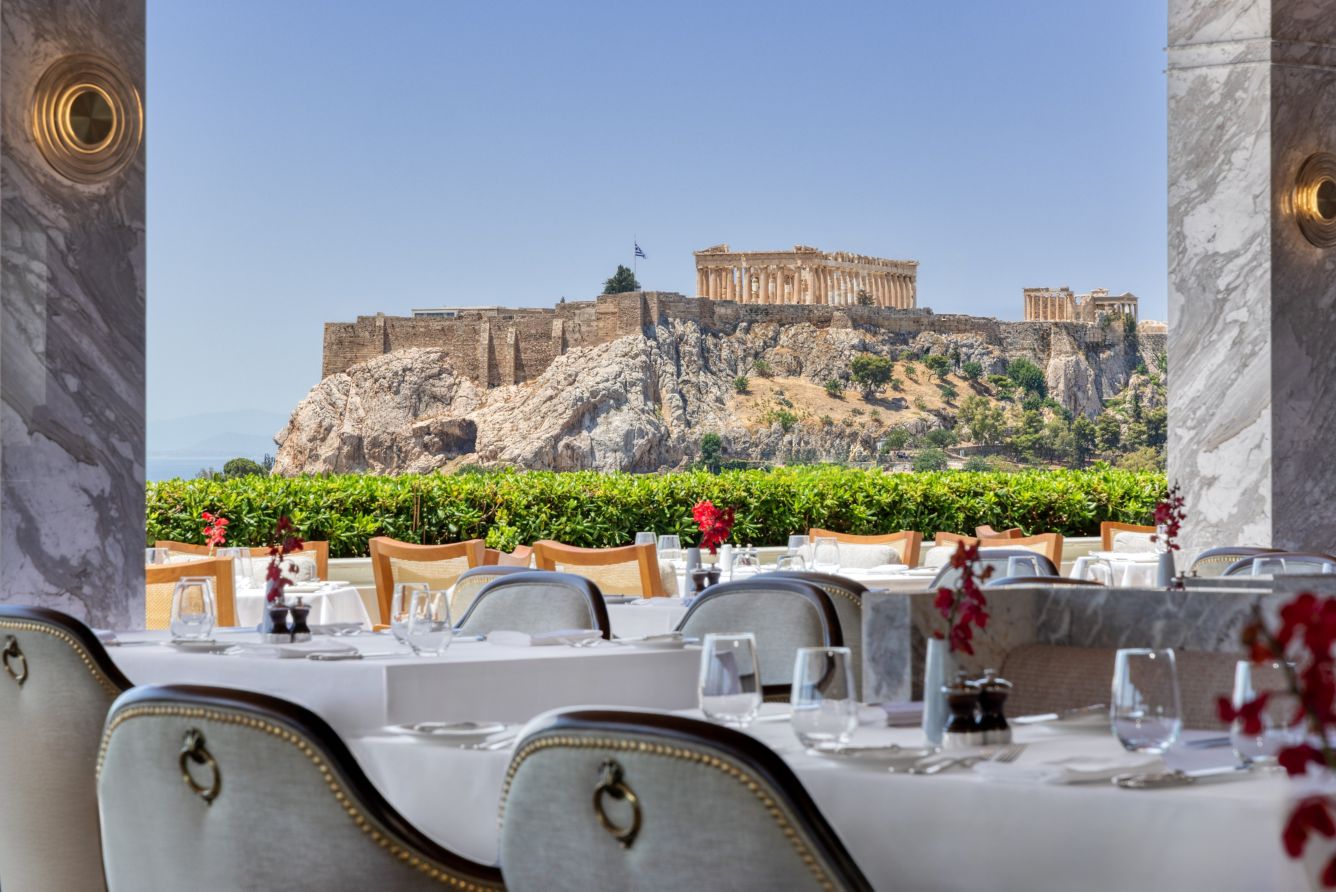 Vintage car parked with Athens' Acropolis in the background.