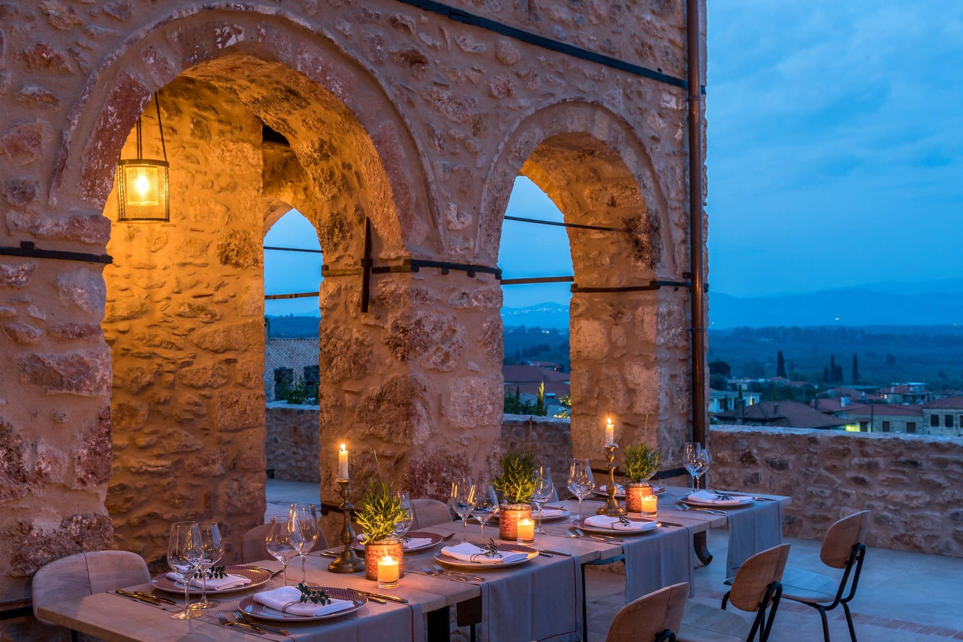 Elegant outdoor dining under warm lights at ancient stone arches.