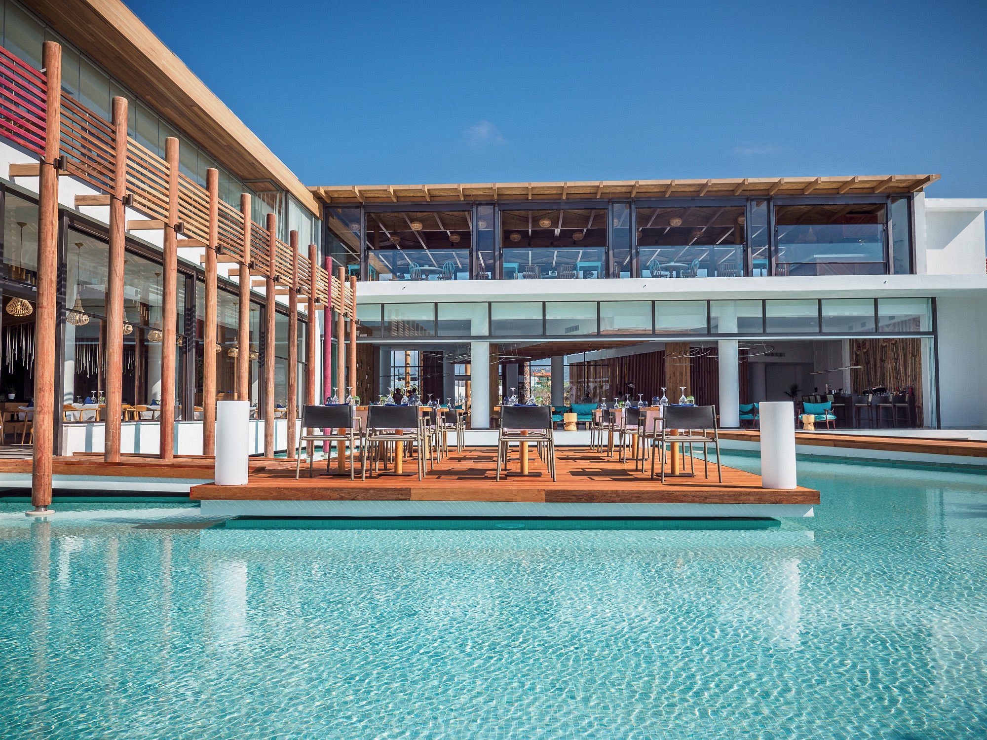 Modern outdoor pool area with wooden deck and seating under a large canopy.
