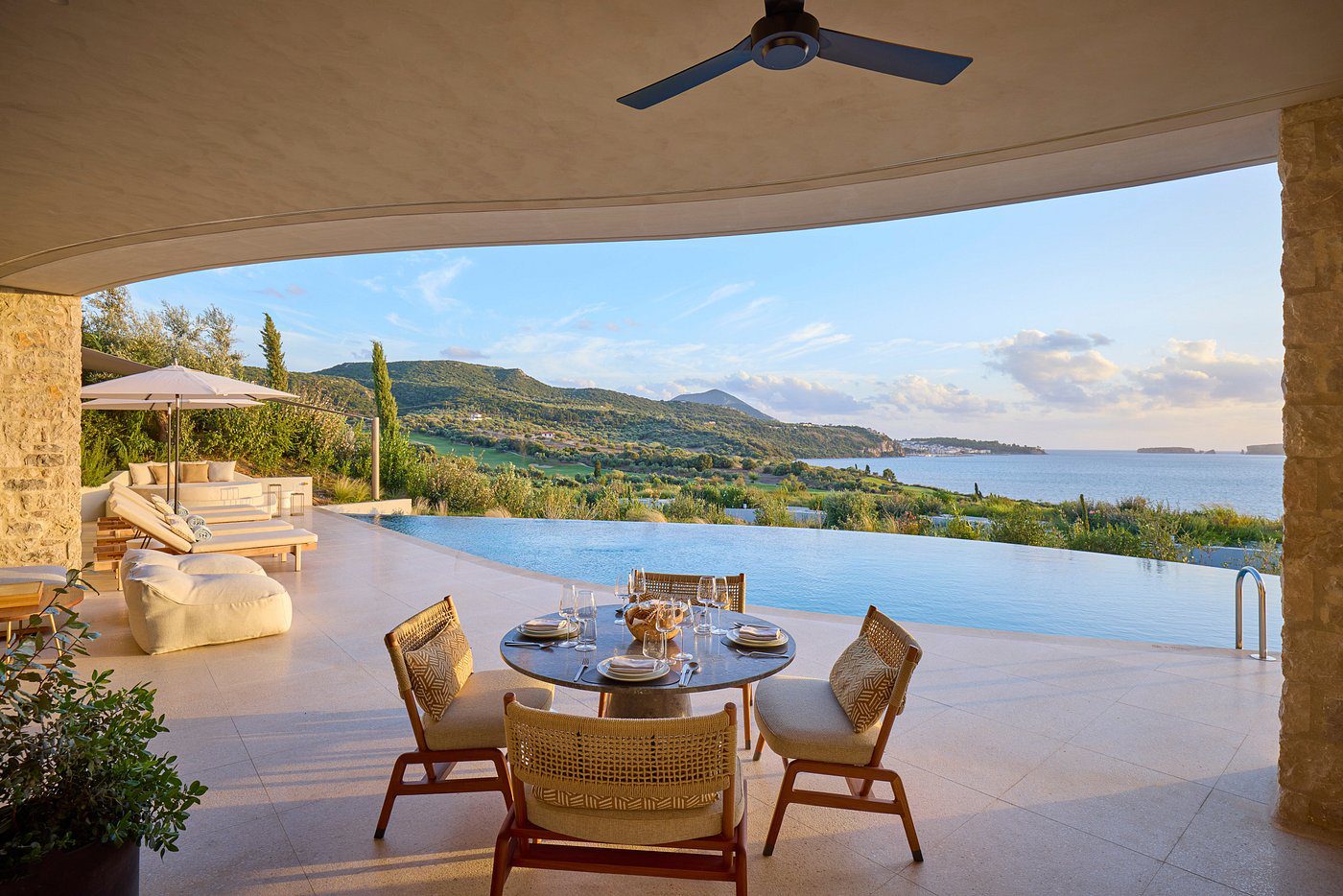 Outdoor dining area overlooking an infinity pool and scenic mountains.
