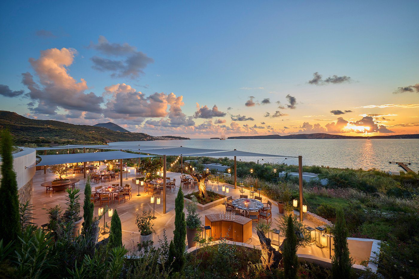 Scenic sunset view over a lively coastal resort with lush greenery and water.