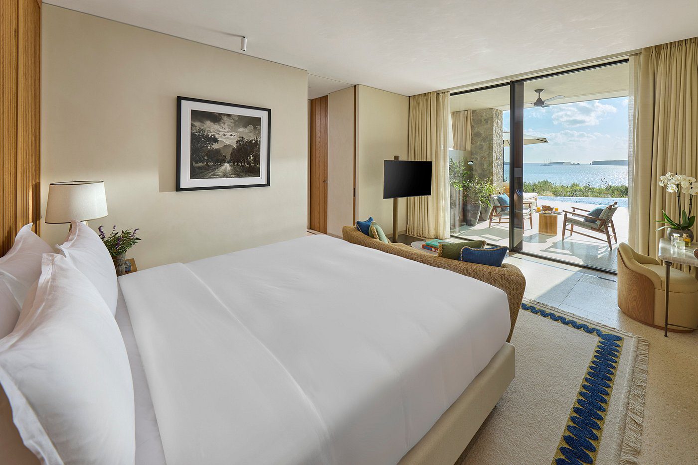 Cozy hotel room with a large bed and balcony overlooking the ocean.