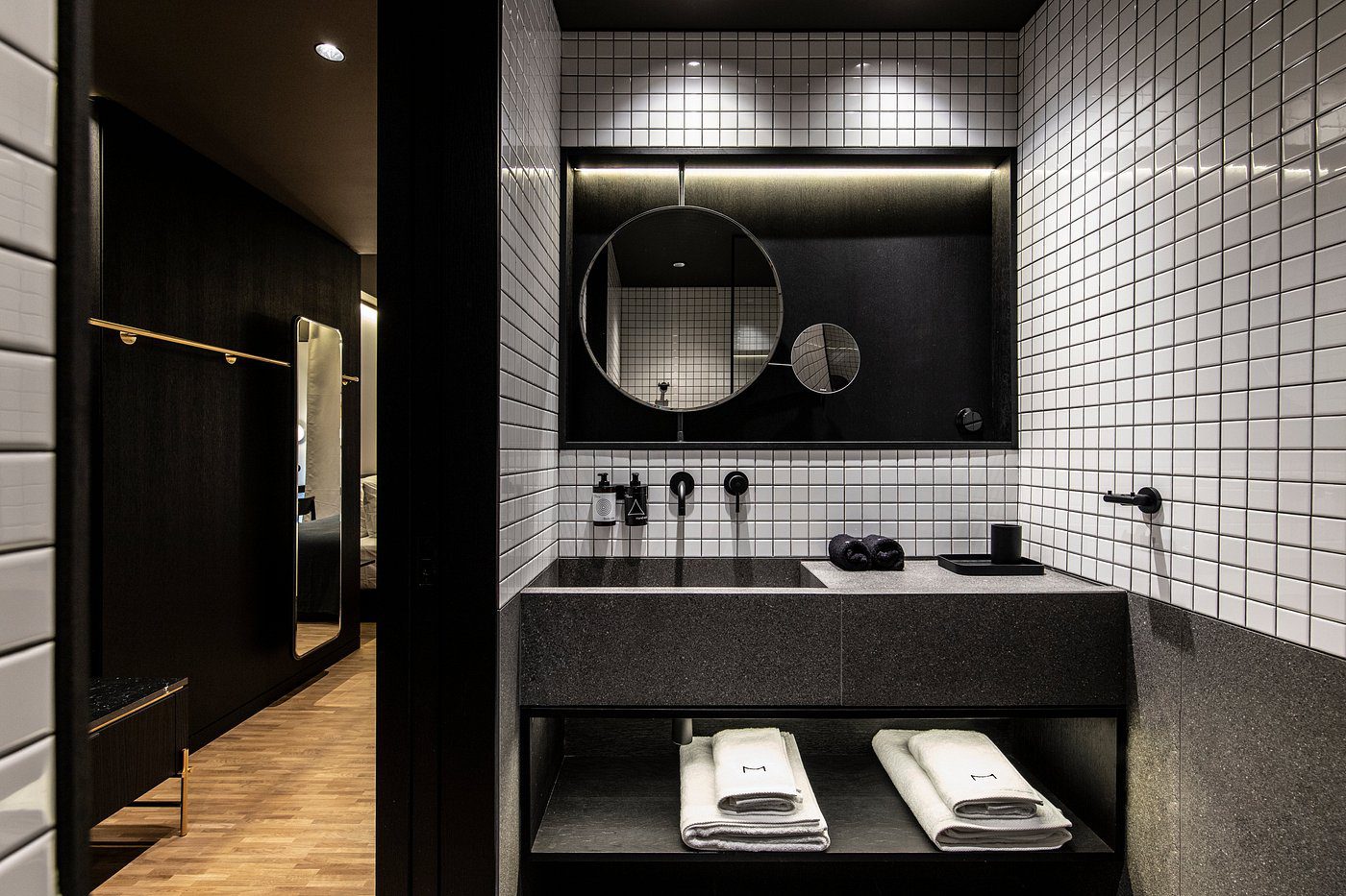 Modern bathroom with black and white design and round mirrors.