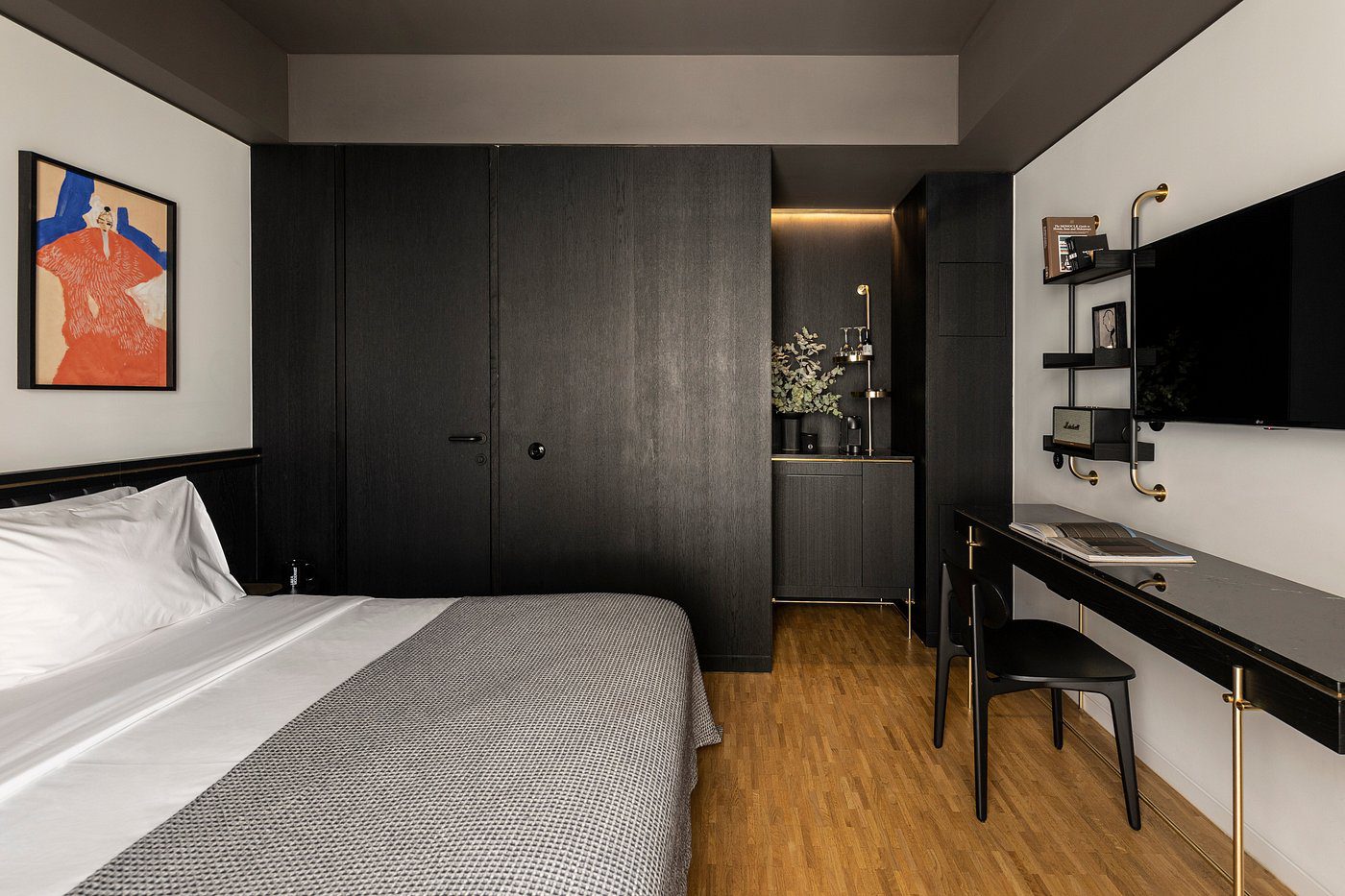 Modern bedroom with dark wardrobe and wooden flooring.