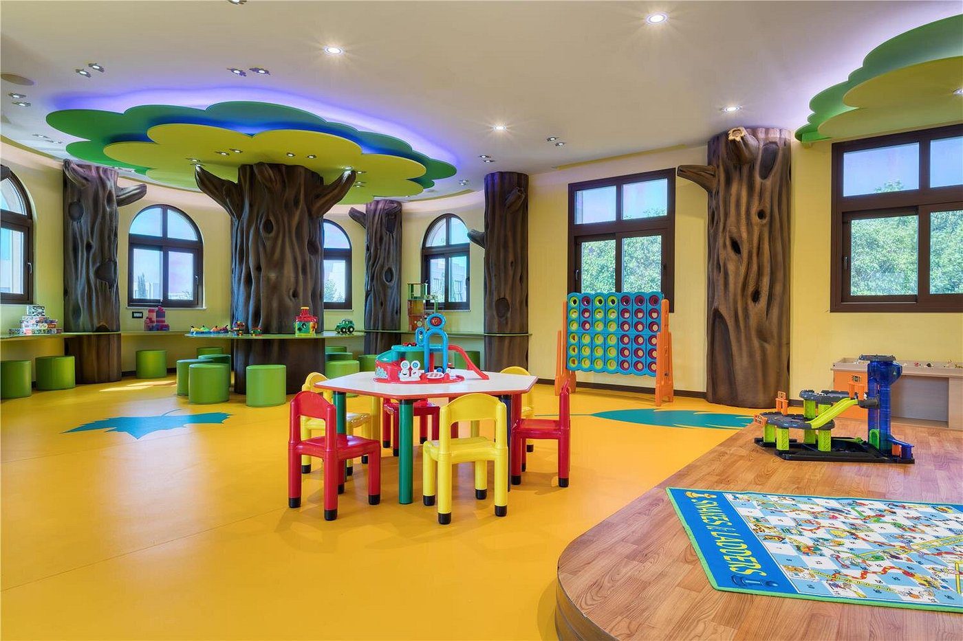 Colorful and inviting children's playroom with tree-themed decor and small tables.