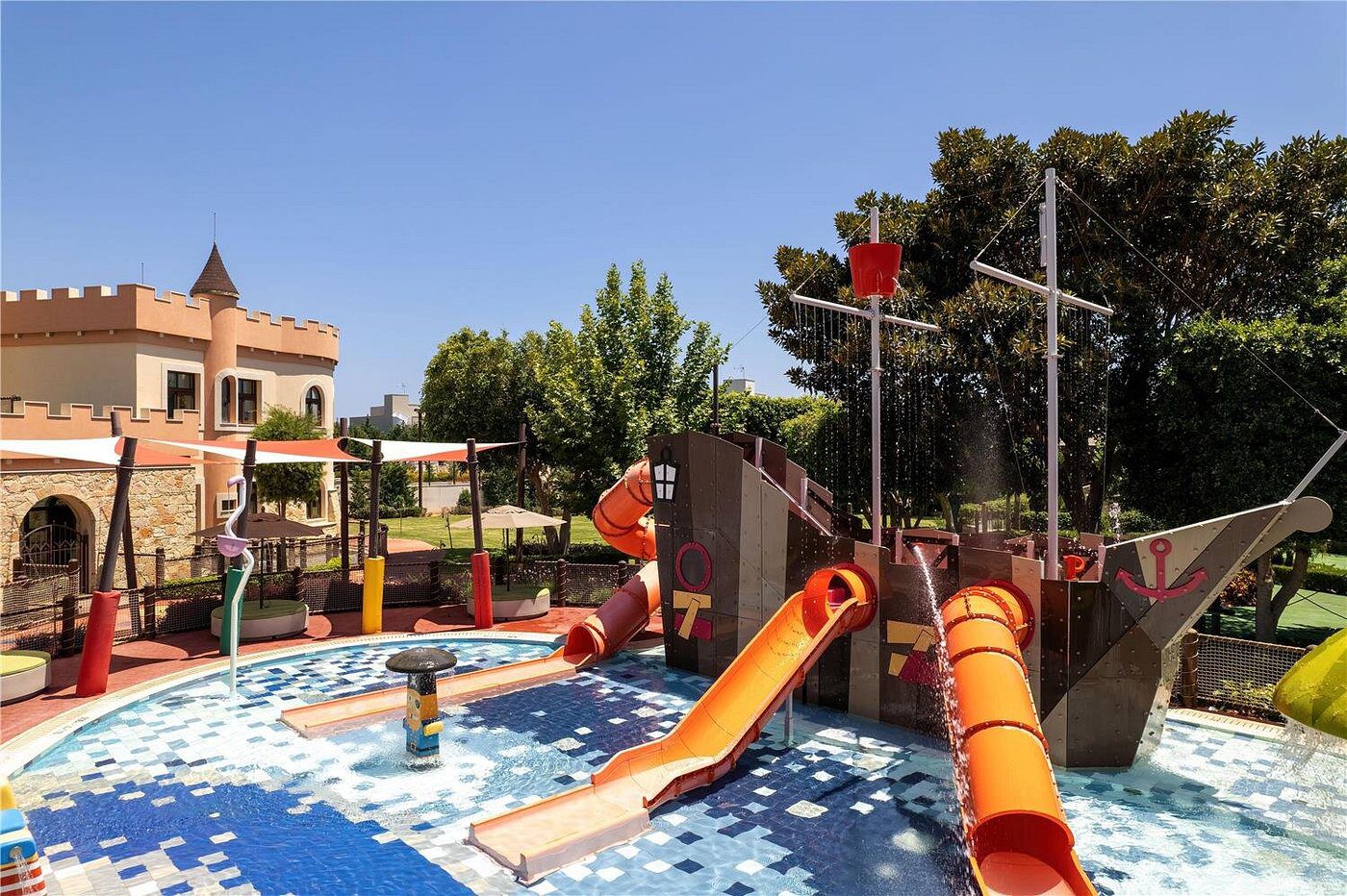 Colorful outdoor water playground with slides and splash areas under clear blue sky.