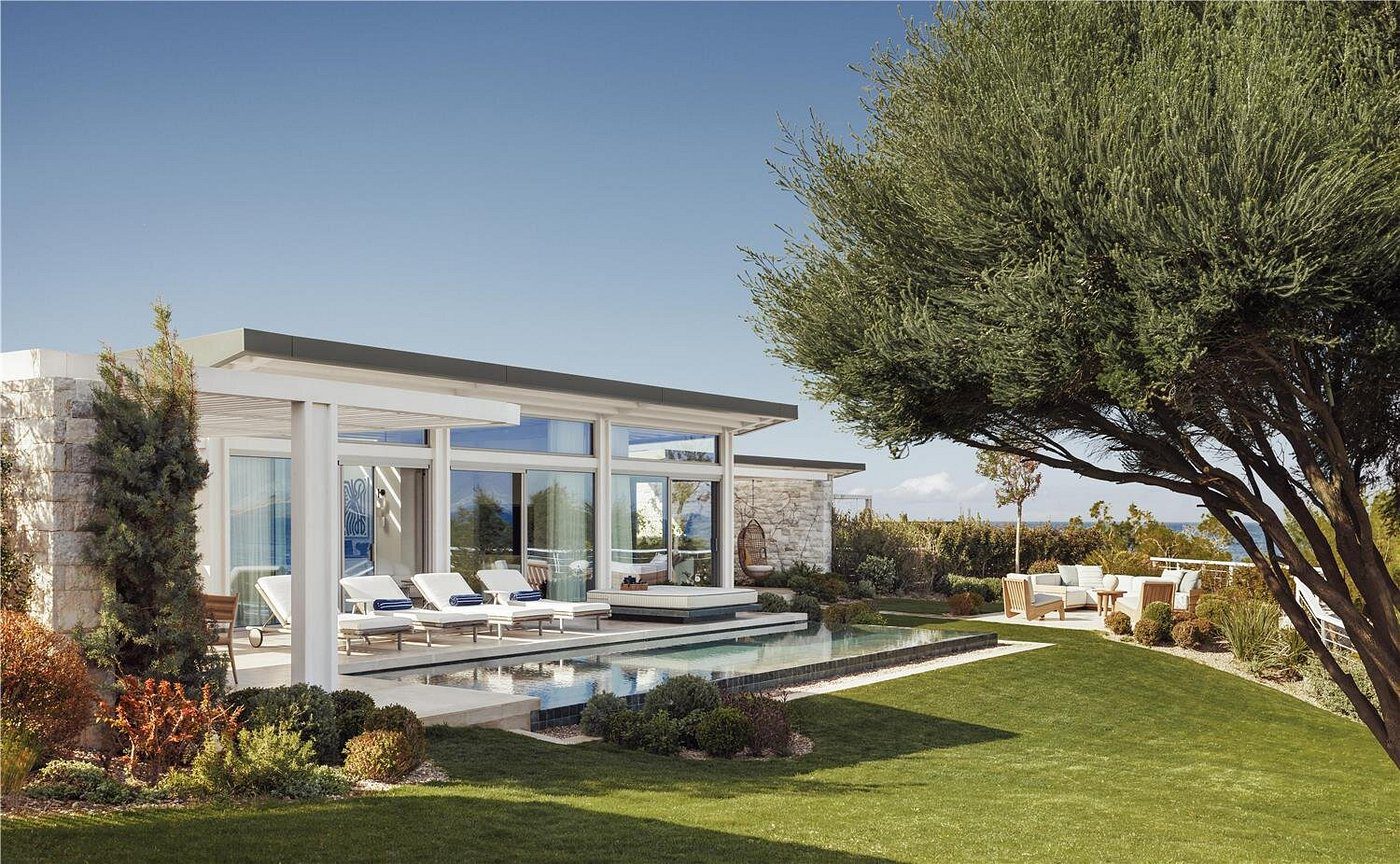 Modern house with pool and outdoor seating under clear sky.