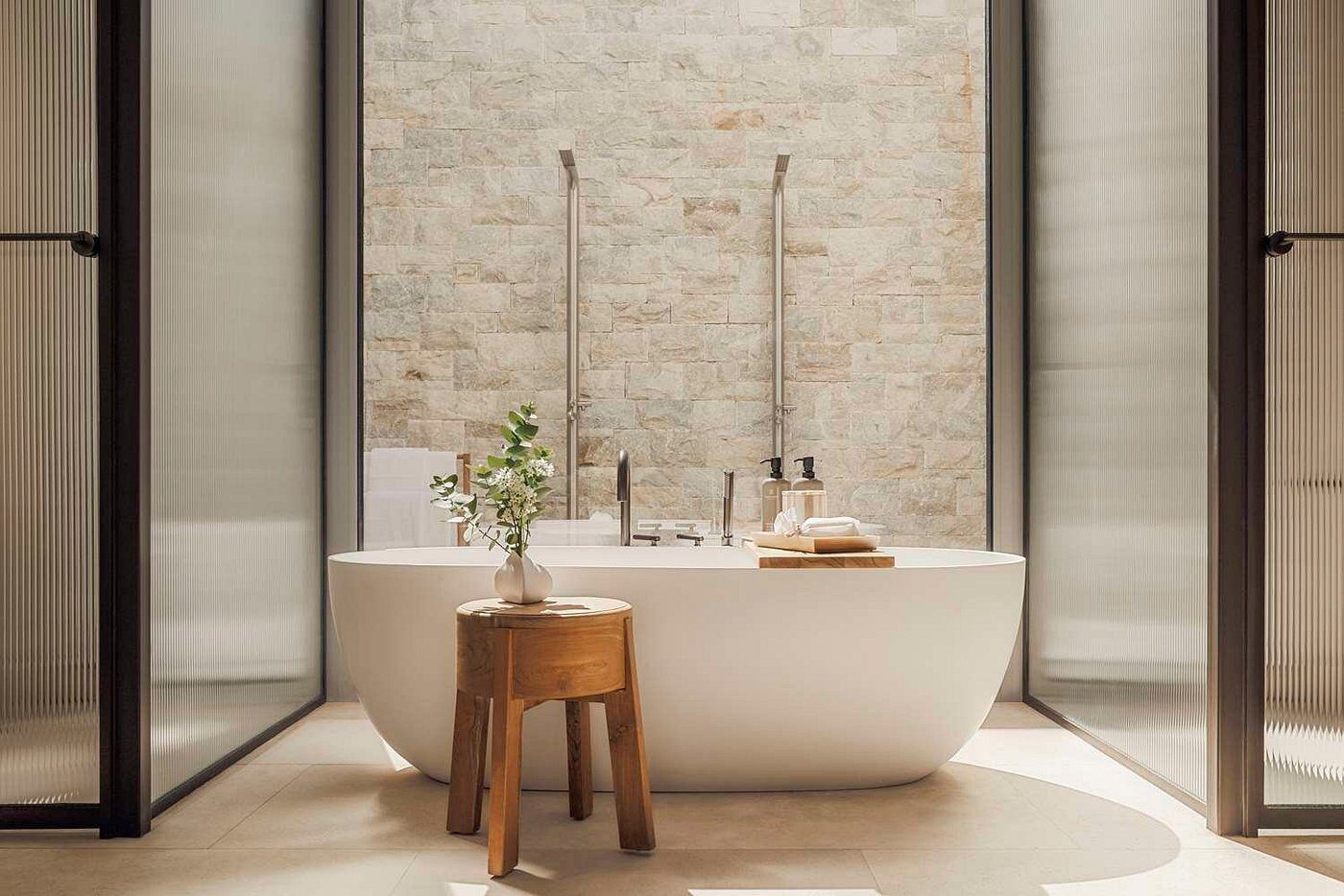 Minimalist bathroom with a freestanding bathtub and wooden stool.
