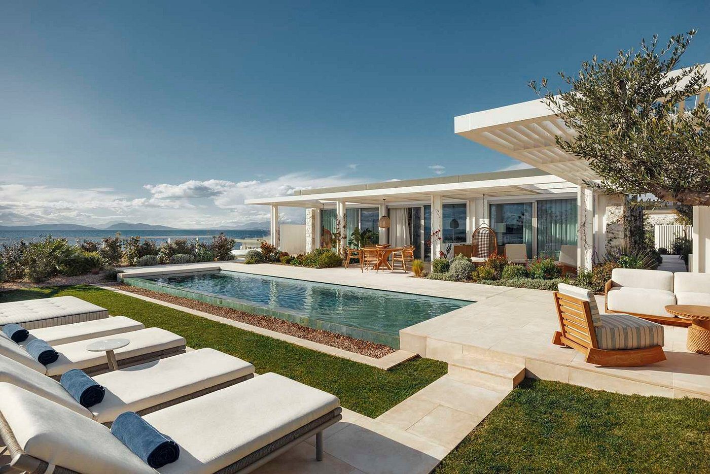 Modern house with a pool and lounge chairs under a clear sky.