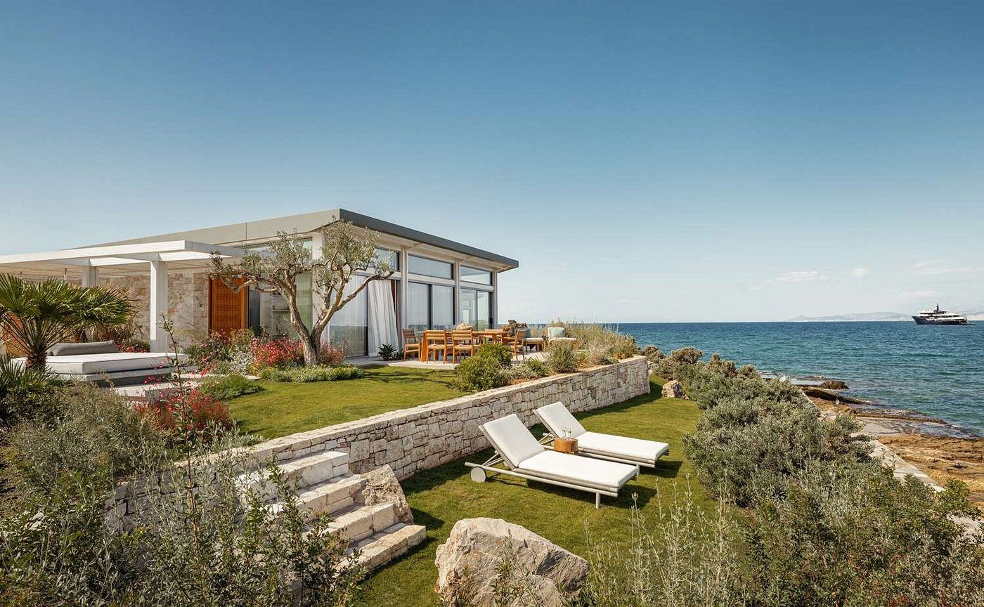 Modern seaside house with lounge chairs overlooking the ocean.