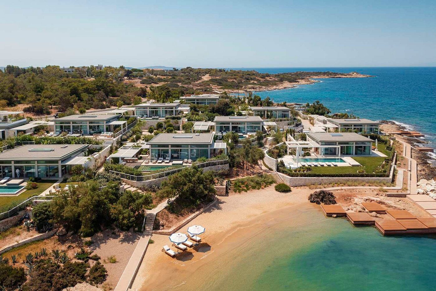 Aerial view of a luxury beachfront resort with pools and sandy beach.