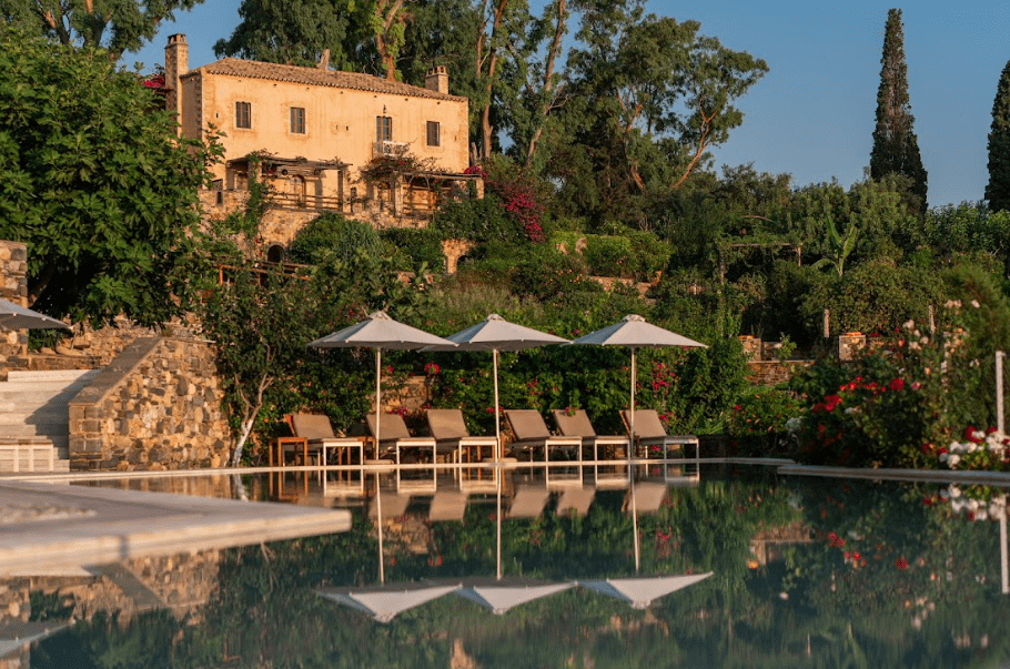 Elegant poolside seating with umbrellas and lush greenery at sunset.