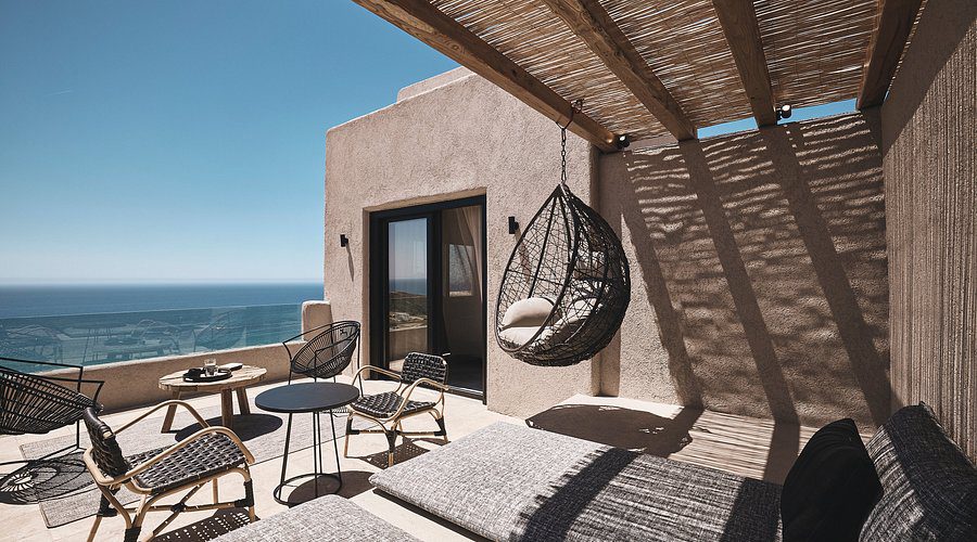 Cozy patio with hanging chair overlooking the sea on a sunny day.