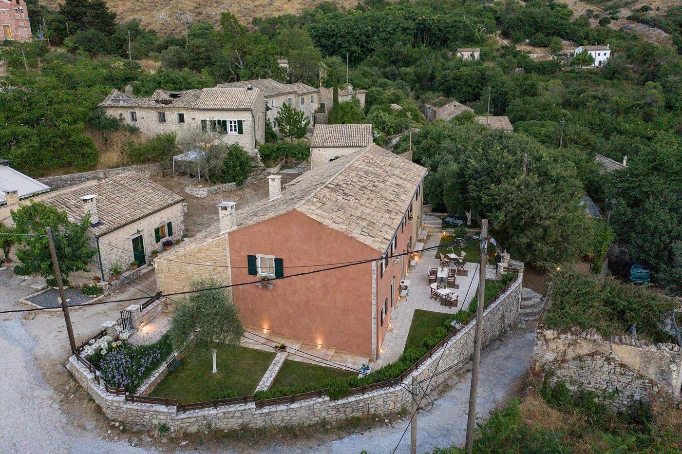 A rustic house with a red brick wall surrounded by greenery and stone pathways.