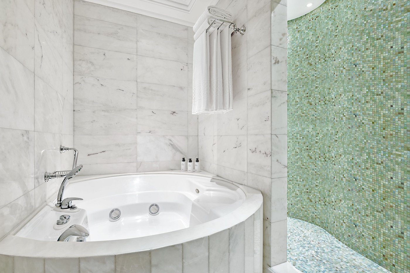 Luxurious white marble bathroom with a large jacuzzi tub and glass shower.