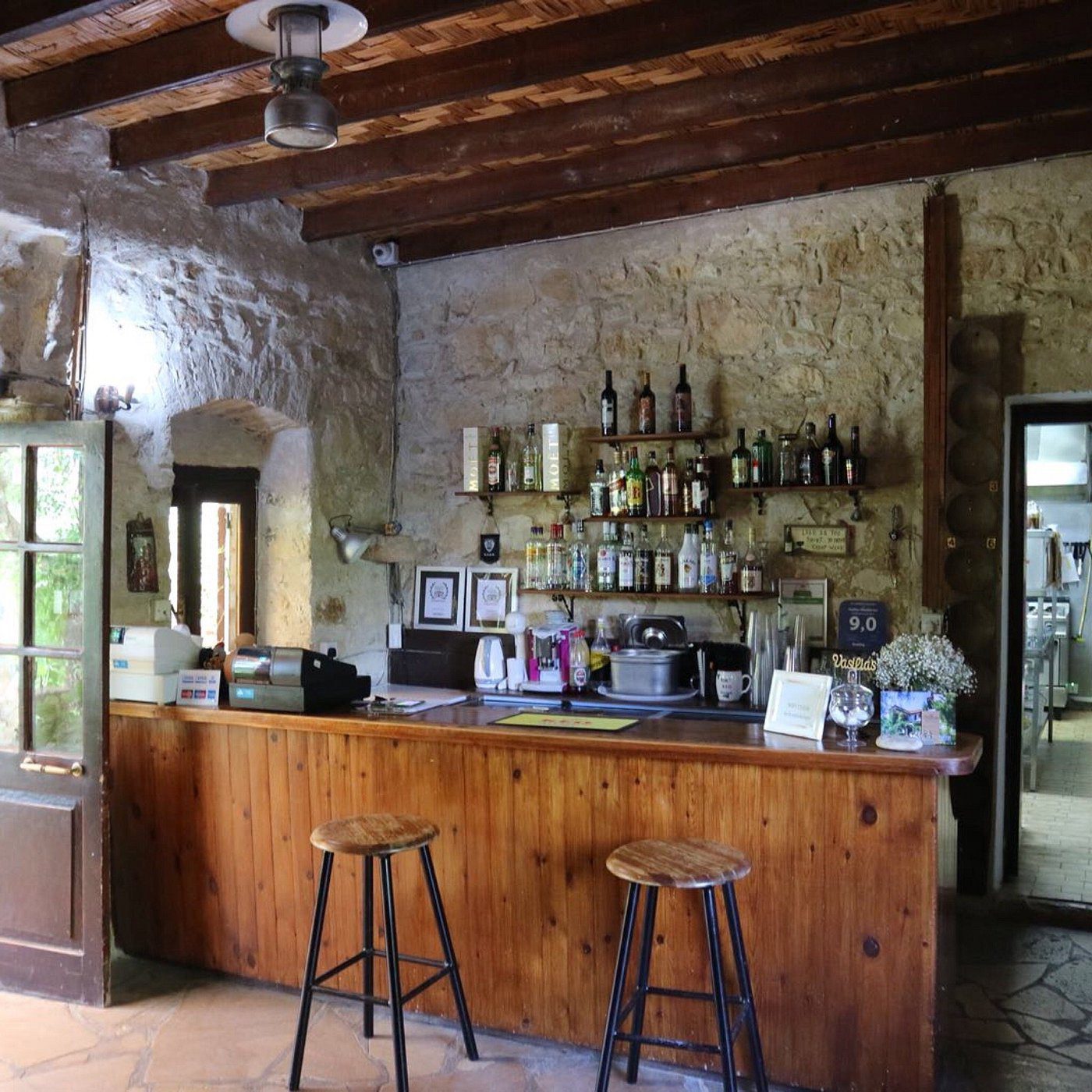 Cozy rustic bar with wooden counter and stools under exposed wooden beams.