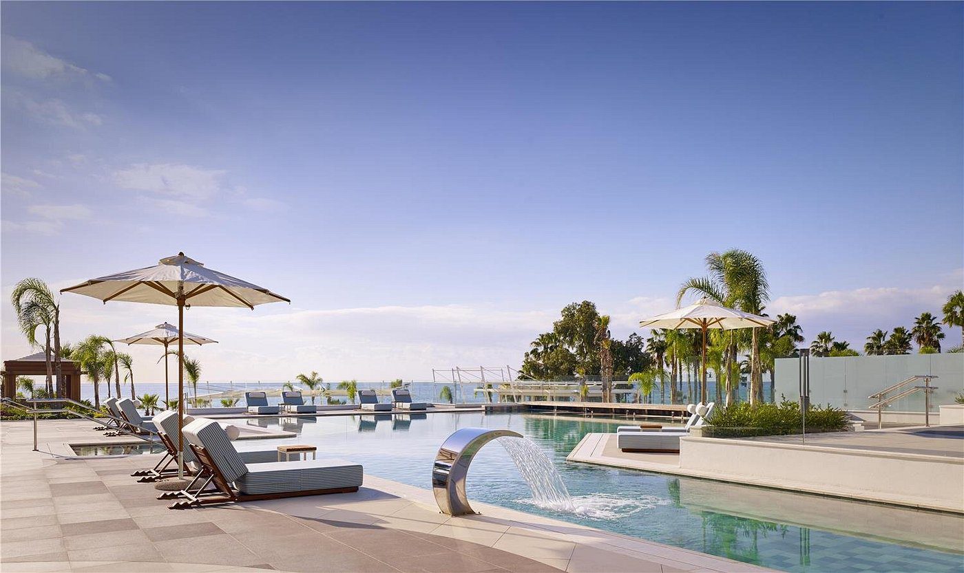Luxurious poolside area with sun loungers and ocean view under a clear sky.