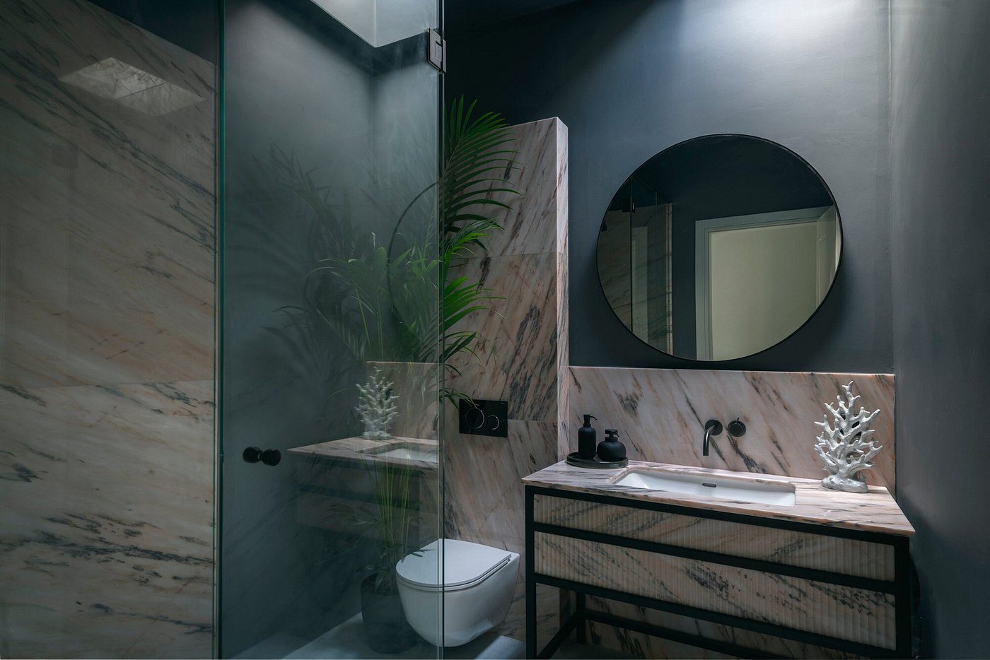 Modern bathroom with glass shower and round mirror.