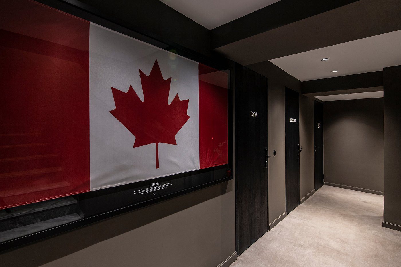 Canadian flag displayed in a hallway with restroom signs.