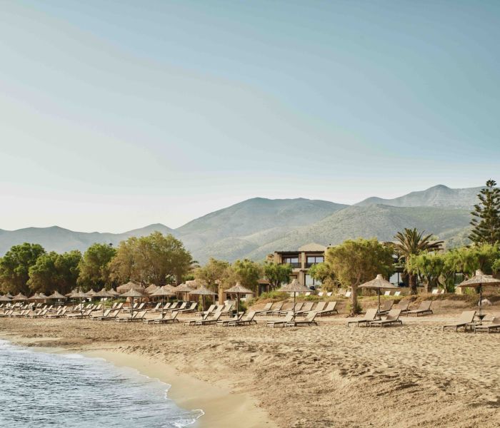 Quiet beach with mountains in the background under a clear sky.