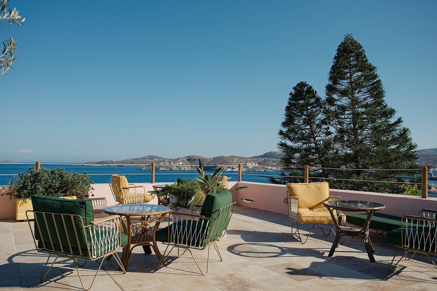 Outdoor patio with tables, chairs, and a scenic waterfront view under a clear sky.