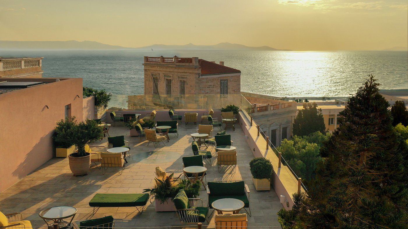 Sunset view of an outdoor terrace with tables overlooking the sea.