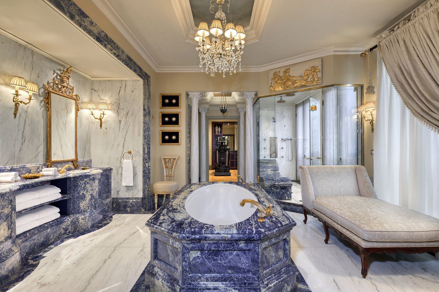 Luxurious bathroom with marble finishes and elegant chandelier.