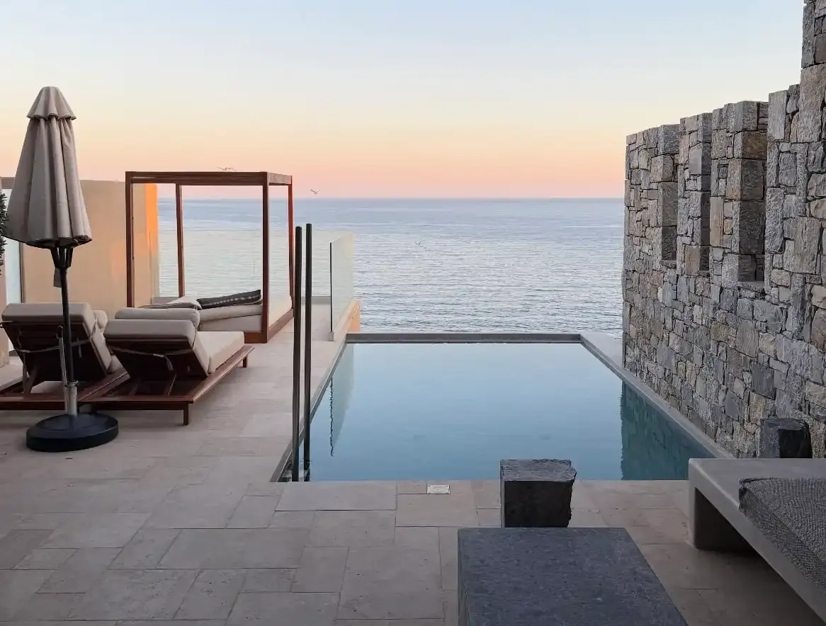 Infinity pool overlooking a calm ocean at sunset.