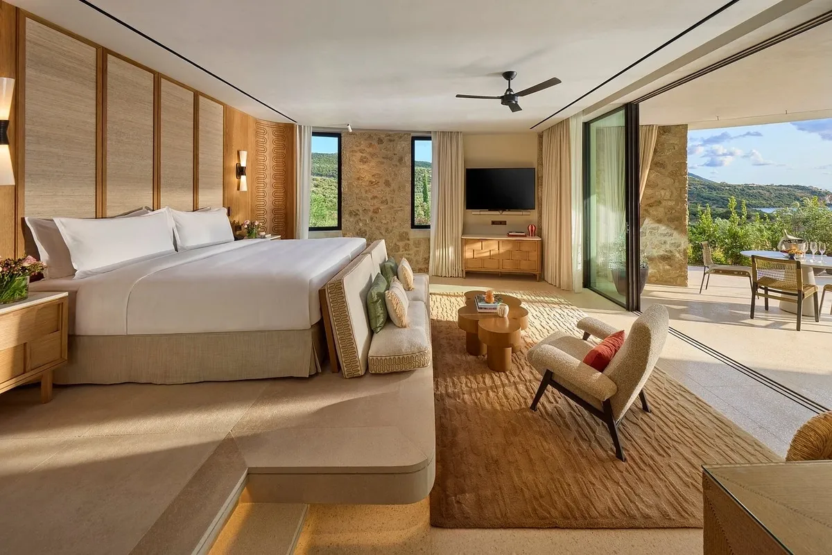 Modern hotel room with large bed and glass wall.