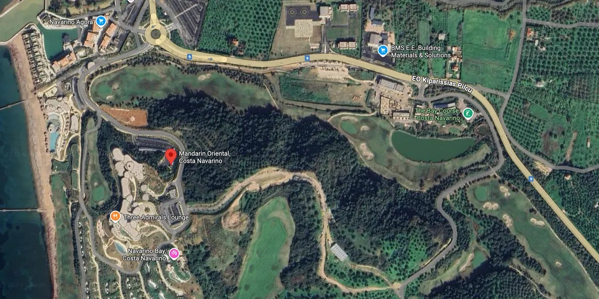 Aerial view of a winding river surrounded by forest and some buildings.