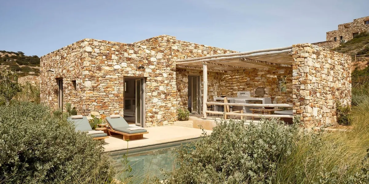 Modern stone house with pool and outdoor seating area.