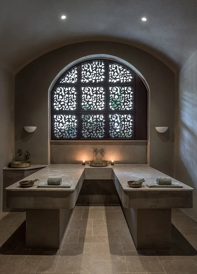 A serene, dimly lit room with two wooden benches and a decorative arched window.