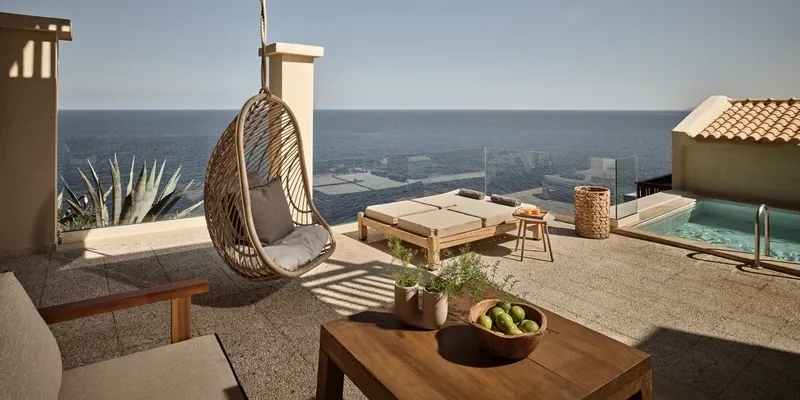 Cozy outdoor patio with a hanging chair and ocean view.