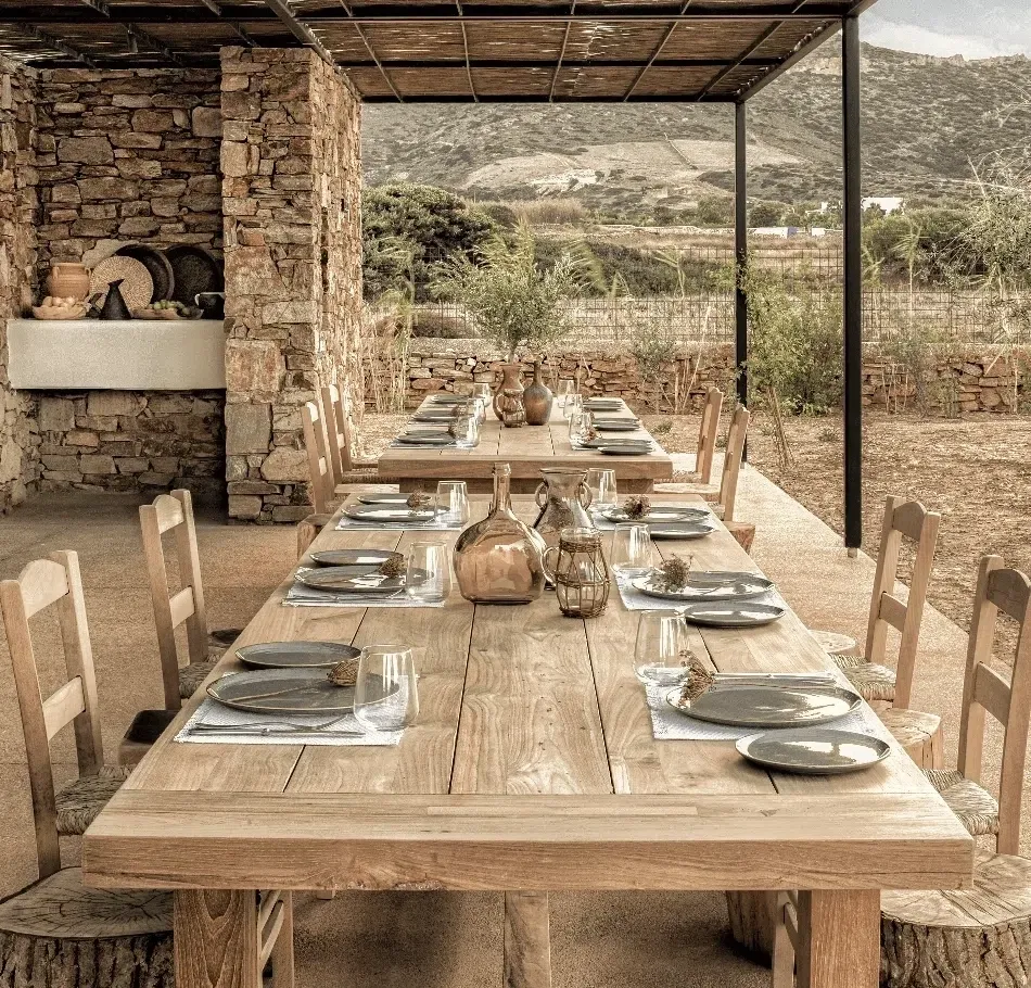 Rustic outdoor dining table set for a meal under a canopy.