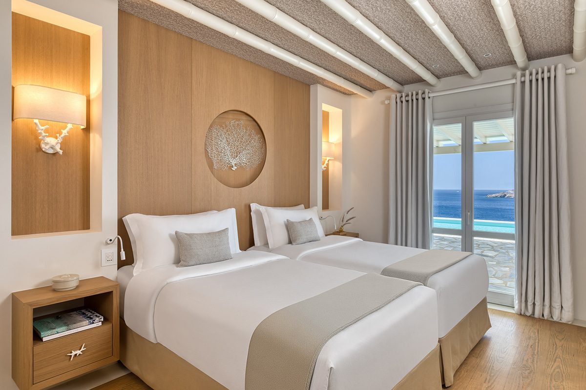 Modern bedroom with twin beds and sea view balcony.