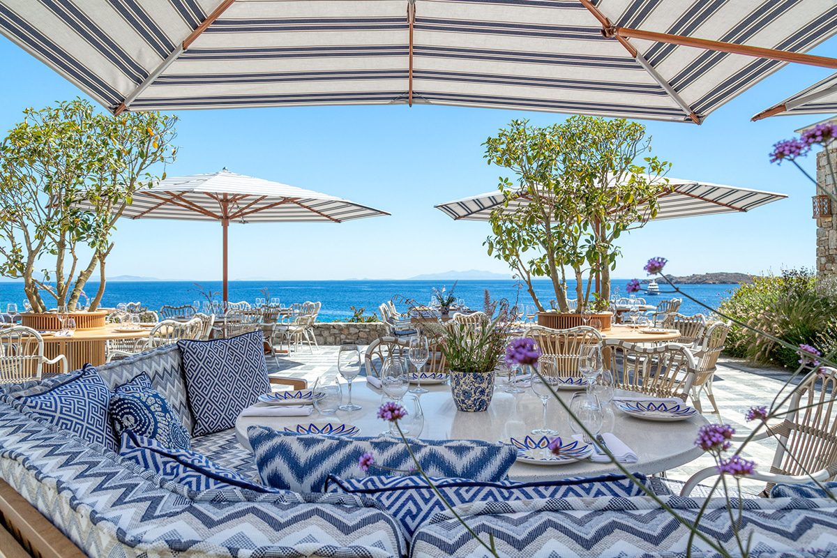 Cozy outdoor dining area with ocean view and patterned cushions.