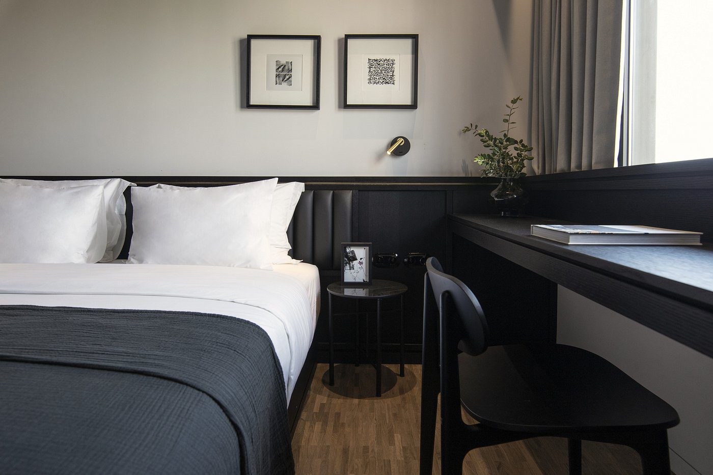 Minimalist bedroom with black and white decor and framed art.