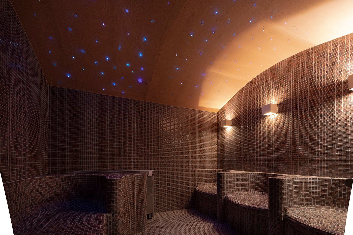 Dimly lit room with tiled walls and star-like ceiling lights.