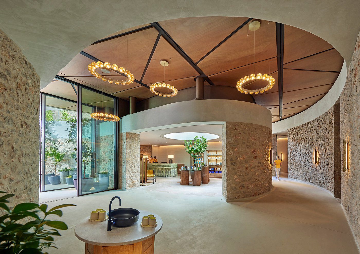 Modern interior with circular chandeliers and stone pillars.