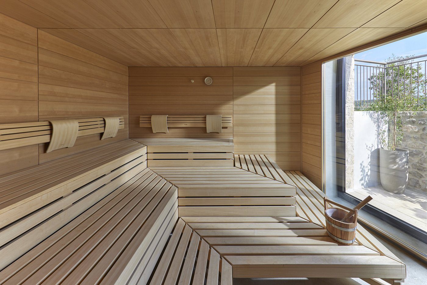 Modern wooden sauna room with tiered benches and a large window.