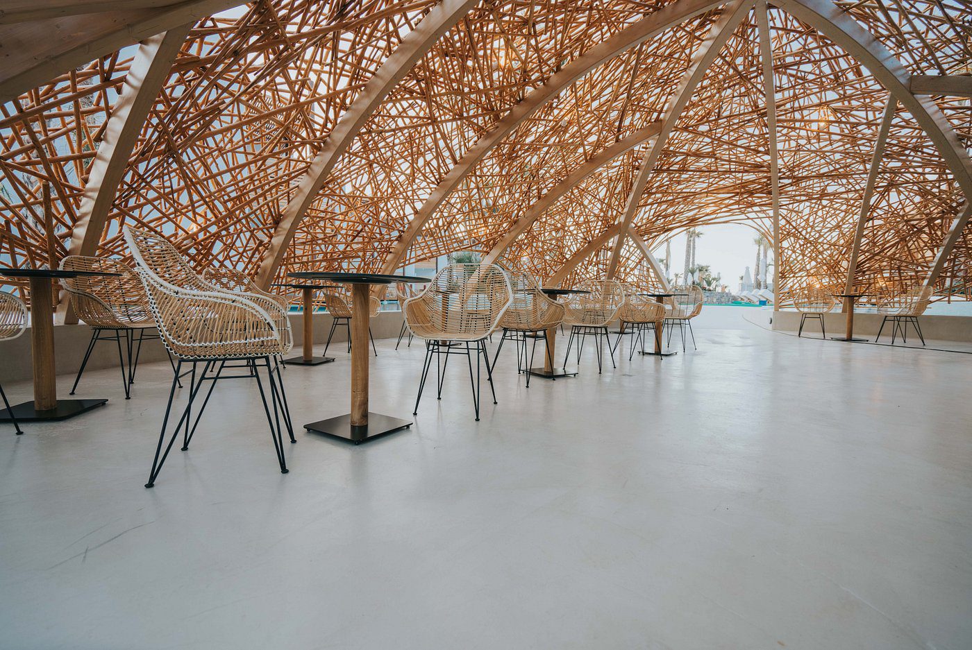 Modern cafe with woven bamboo ceiling and minimalist furniture.