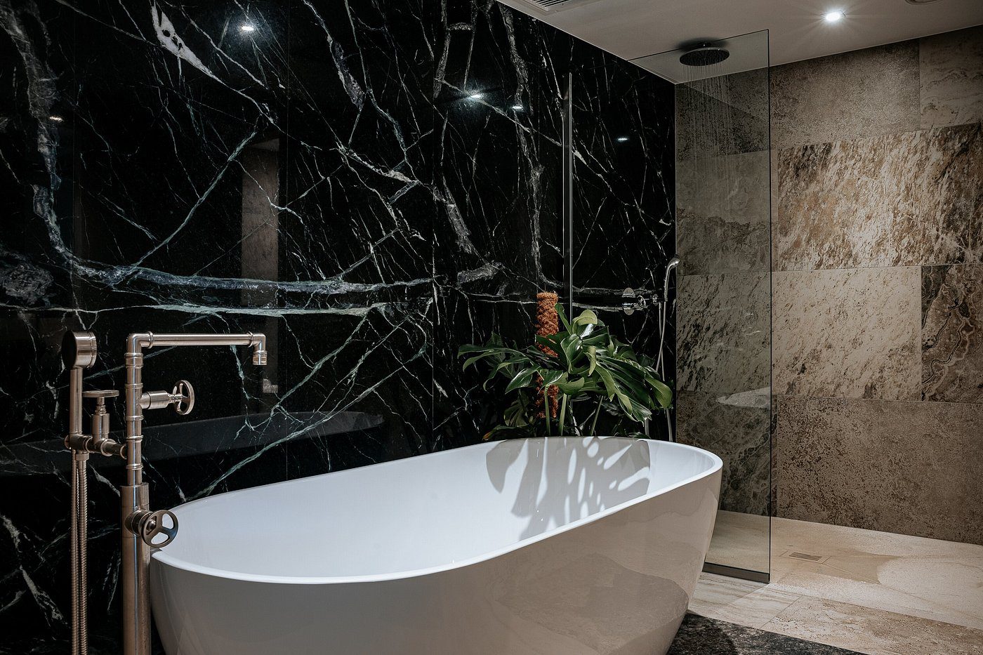 Sleek modern bathroom with a freestanding white tub and black marble wall.