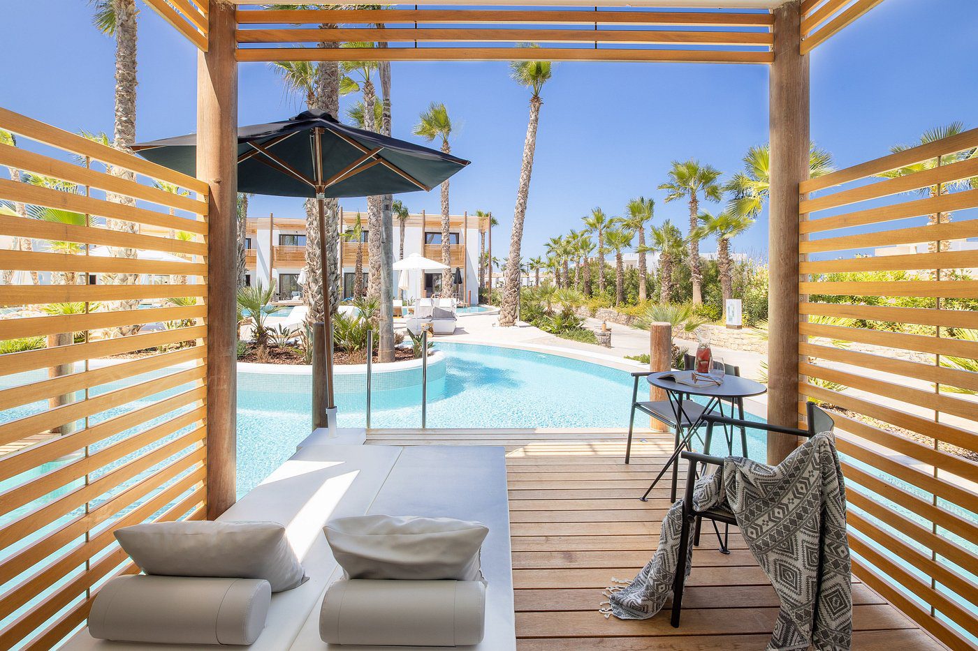 Luxurious poolside area with wooden deck and modern seating under a pergola.