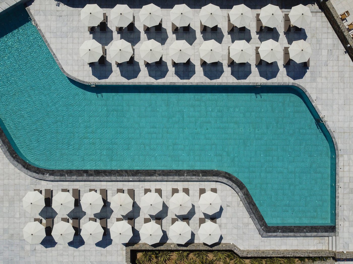 Aerial view of a swimming pool with white umbrellas and lounge chairs.