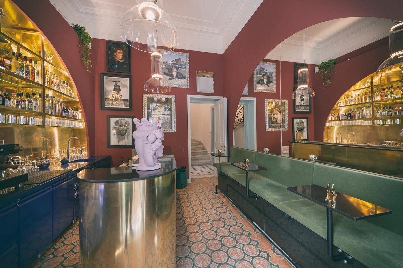 Elegant vintage-themed restaurant interior with green seating and art on red walls.