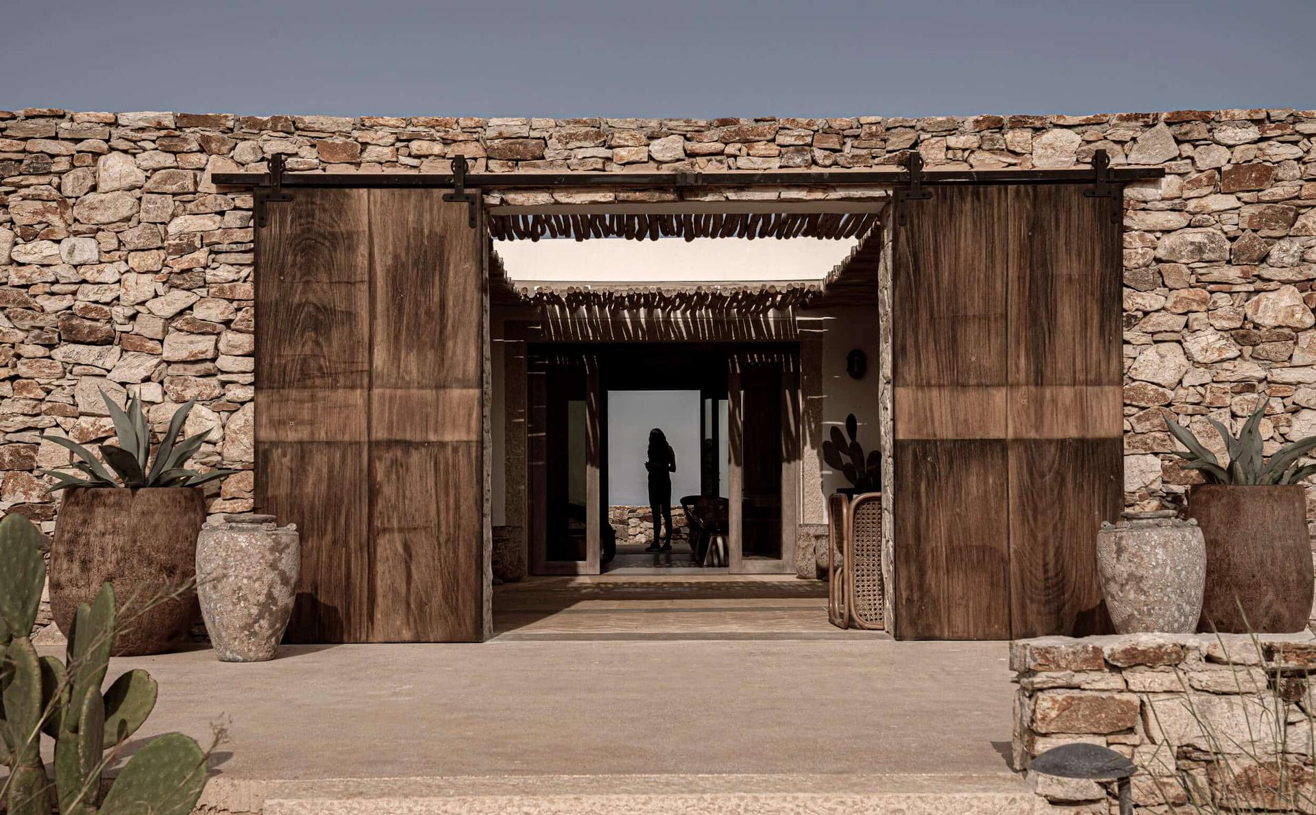 Entrance to an ancient stone structure with wooden doors and a shadowed interior.
