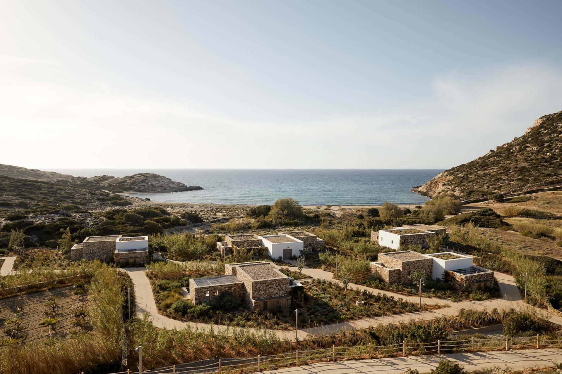 Coastal landscape with scattered buildings and calm sea under a clear sky.