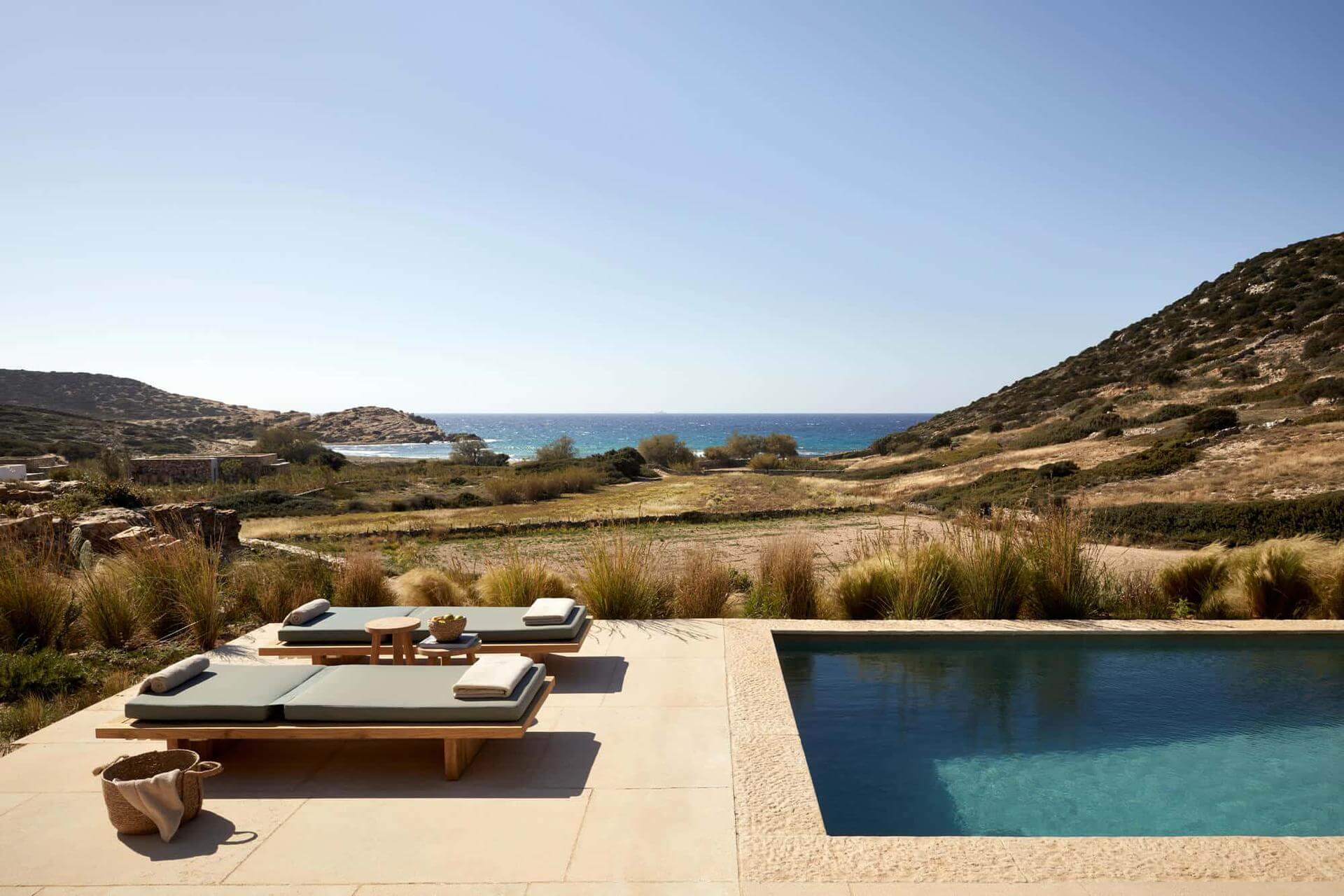 Luxury poolside lounge with ocean views and sunbeds.